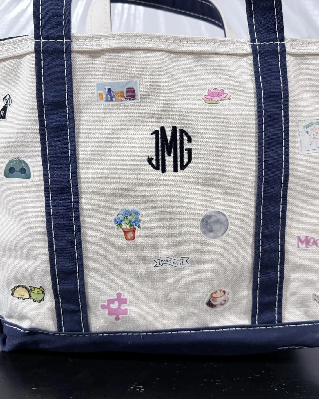 Navy-trimmed boat tote with a monogram and stickers